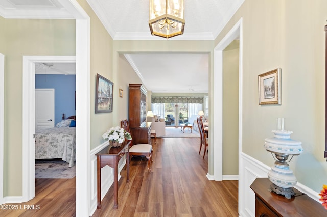 foyer featuring a notable chandelier, ornamental molding, baseboards, and wood finished floors