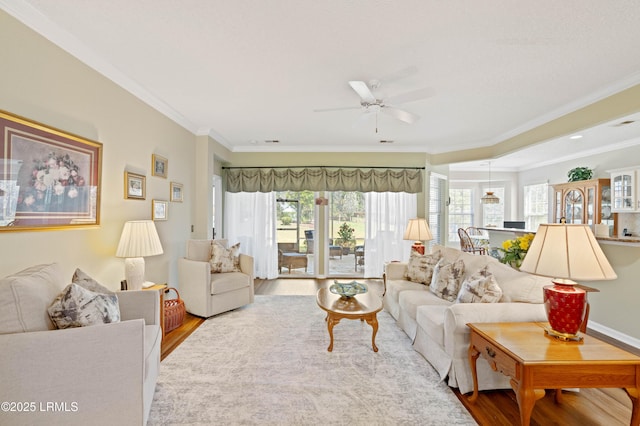 living room featuring wood finished floors, a ceiling fan, and ornamental molding
