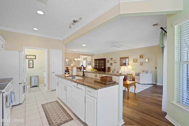 kitchen featuring visible vents, open floor plan, ornamental molding, white appliances, and a sink