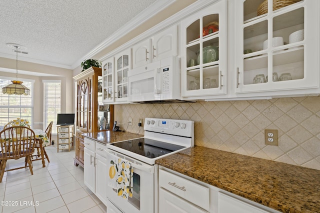 kitchen with pendant lighting, white cabinetry, white appliances, light tile patterned floors, and glass insert cabinets