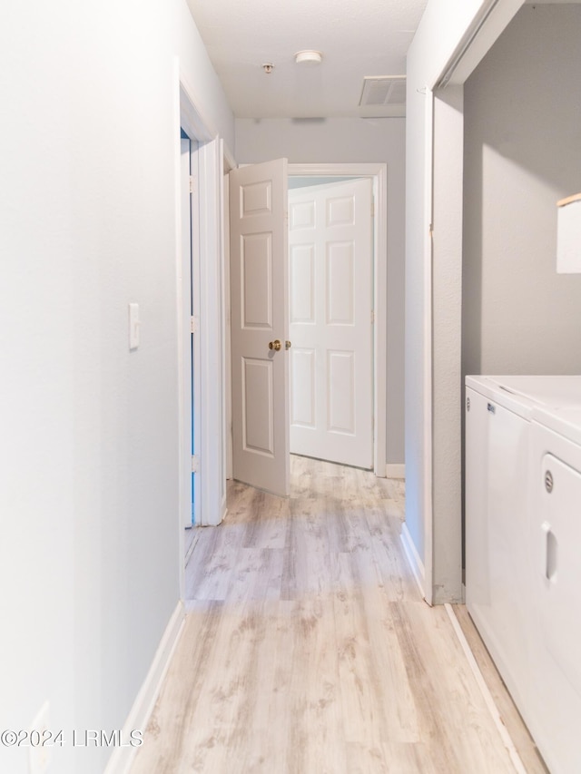 corridor with washer and clothes dryer and light wood-type flooring