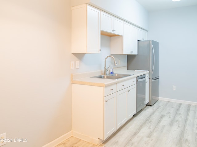 kitchen with light wood-type flooring, stainless steel dishwasher, sink, and white cabinets