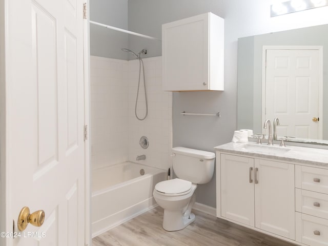 full bathroom with vanity, hardwood / wood-style flooring, toilet, and tiled shower / bath