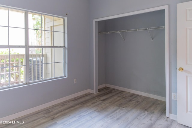 unfurnished bedroom with multiple windows, light hardwood / wood-style flooring, and a closet