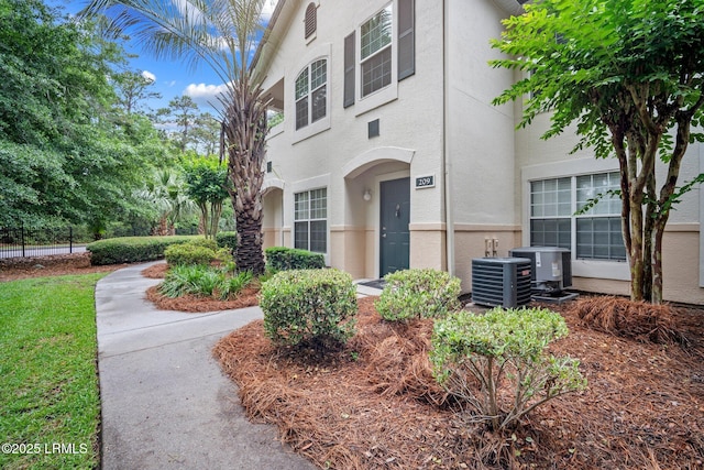 897 Fording Island Rd Unit 209, Bluffton, SC 29910 - view of property exterior featuring stucco siding, central AC unit, and fence
