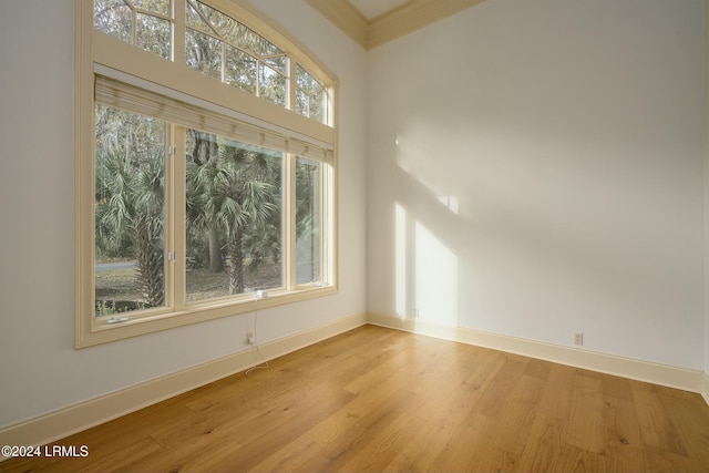 spare room with baseboards, crown molding, and wood finished floors