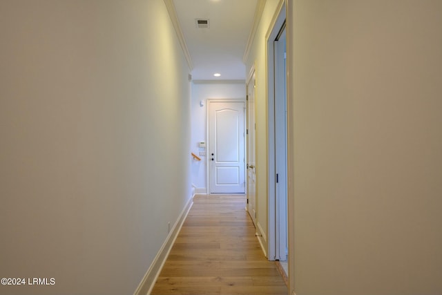 hallway with ornamental molding and light hardwood / wood-style floors