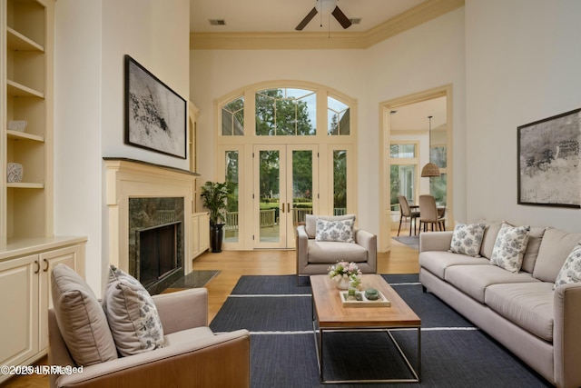 living area with ornamental molding, french doors, a ceiling fan, light wood-style floors, and visible vents