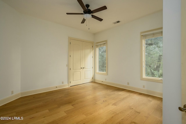 empty room featuring visible vents, light wood-style flooring, ceiling fan, and baseboards