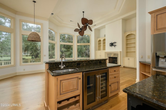 kitchen featuring wine cooler, sink, light hardwood / wood-style flooring, stainless steel fridge, and dark stone counters