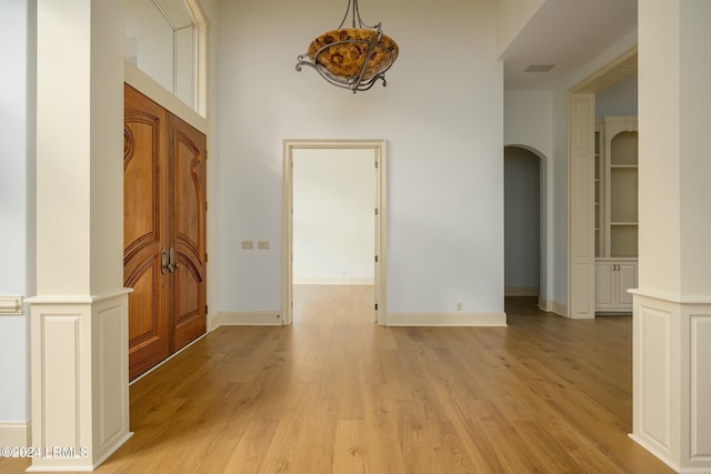 corridor featuring decorative columns, light hardwood / wood-style flooring, and built in shelves