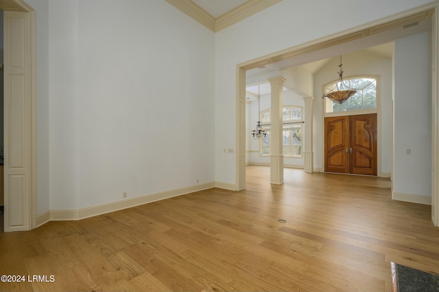 interior space featuring ornamental molding, decorative columns, and light wood-type flooring