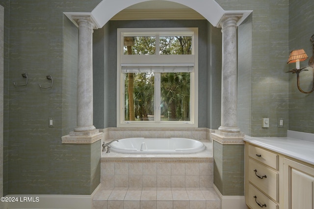 bathroom featuring decorative columns, vanity, and tiled tub