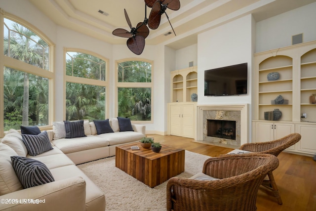 living area featuring a towering ceiling, visible vents, wood finished floors, and ceiling fan