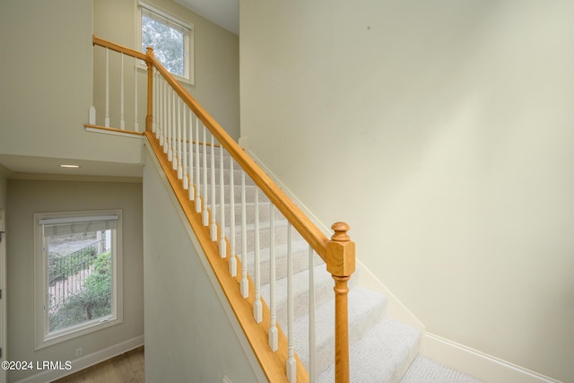 stairs with a healthy amount of sunlight and hardwood / wood-style floors