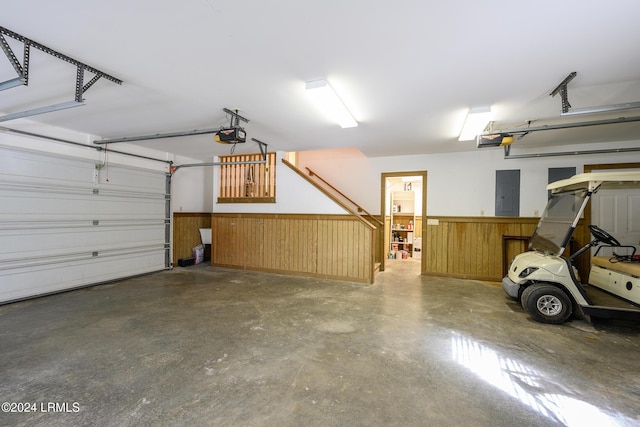 garage with a garage door opener, electric panel, and wood walls