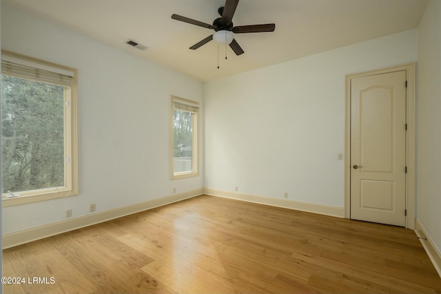 spare room with visible vents, light wood-style flooring, a ceiling fan, and baseboards