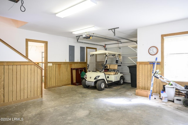 garage with wooden walls, a garage door opener, wainscoting, and electric panel