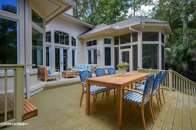 wooden deck featuring an outdoor living space with a fire pit, french doors, outdoor dining area, and a sunroom