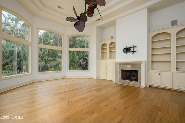 unfurnished living room featuring a high ceiling, ceiling fan, and a high end fireplace