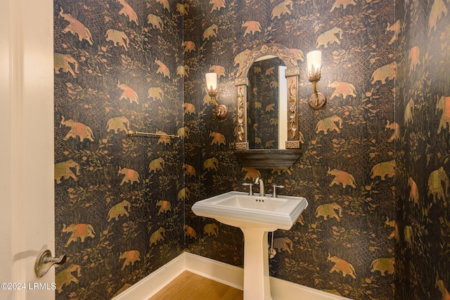 bathroom featuring baseboards, wallpapered walls, and wood finished floors