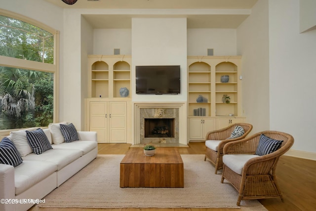 living room with baseboards, a towering ceiling, wood finished floors, and a fireplace