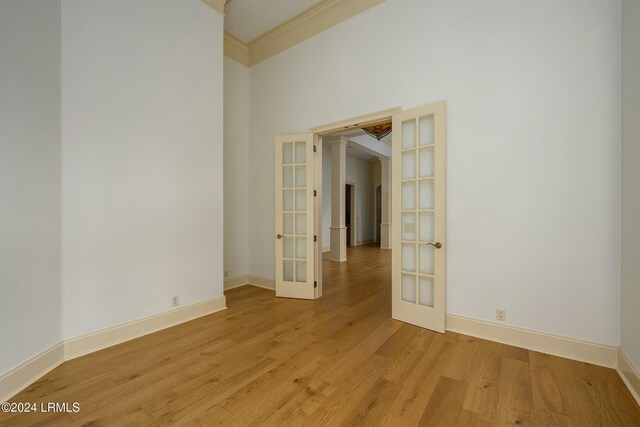 empty room featuring crown molding, french doors, and light wood-type flooring