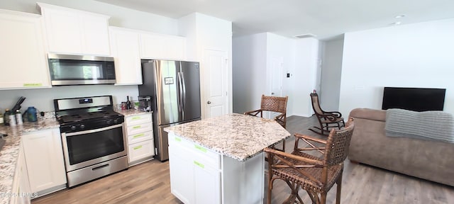 12 Pacolet Ln, Beaufort, SC 29906 - kitchen featuring appliances with stainless steel finishes, a breakfast bar, light stone countertops, light wood-style floors, and white cabinets