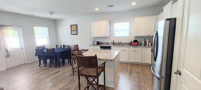 12 Pacolet Ln, Beaufort, SC 29906 - kitchen with freestanding refrigerator, light wood-style flooring, a breakfast bar, light stone counters, and white cabinets