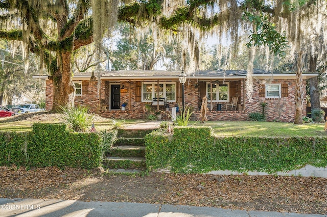 ranch-style house featuring brick siding, a porch, and a front lawn