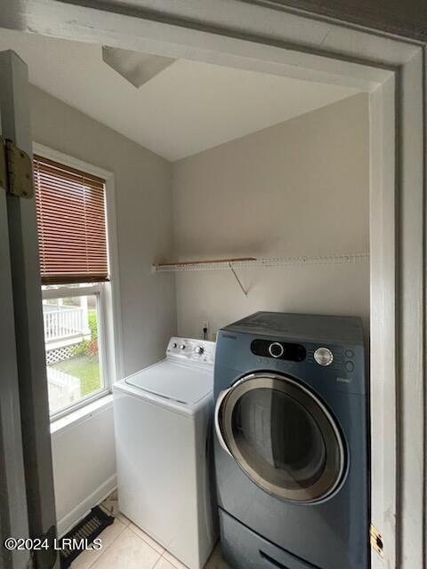 clothes washing area with washer and clothes dryer and light tile patterned floors