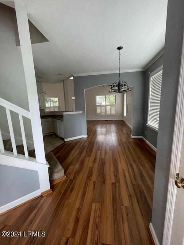 unfurnished dining area featuring ornamental molding, dark hardwood / wood-style flooring, and a notable chandelier