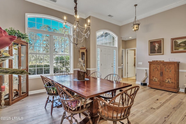 dining space featuring ornamental molding, a wealth of natural light, and light hardwood / wood-style flooring