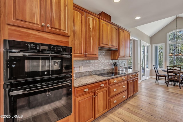 kitchen with stone counters, lofted ceiling, decorative backsplash, black appliances, and light hardwood / wood-style flooring