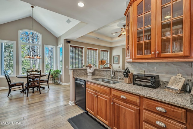 kitchen with sink, hanging light fixtures, dishwasher, light stone countertops, and light hardwood / wood-style floors