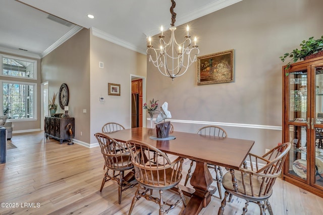 dining room with ornamental molding, light hardwood / wood-style flooring, and a notable chandelier