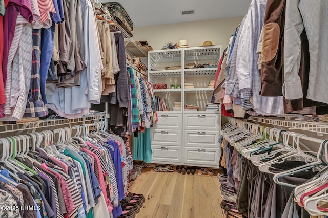 walk in closet with light hardwood / wood-style flooring