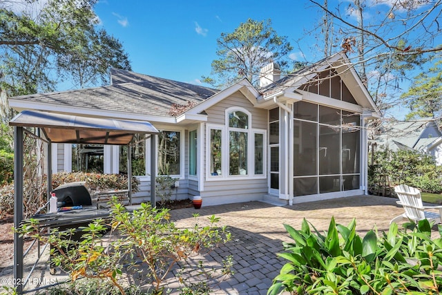 rear view of house featuring a sunroom and a patio area