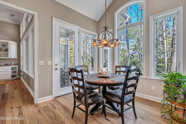 dining area with vaulted ceiling, plenty of natural light, an inviting chandelier, and light hardwood / wood-style floors