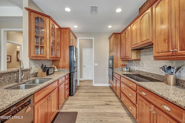 kitchen with light stone countertops, sink, light hardwood / wood-style flooring, and black appliances