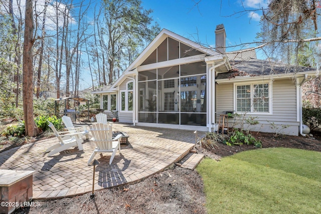 rear view of property featuring a lawn, a sunroom, and a patio