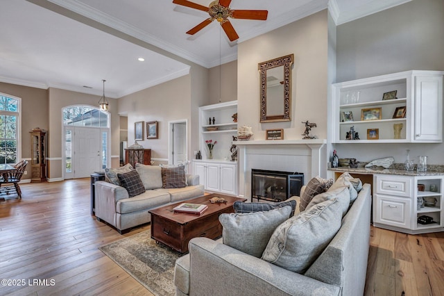 living room with a towering ceiling, light hardwood / wood-style flooring, and ornamental molding