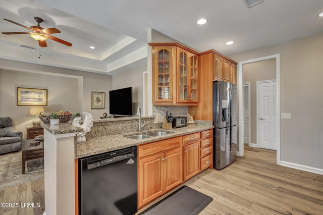 kitchen featuring sink, black dishwasher, stainless steel refrigerator with ice dispenser, light stone counters, and light hardwood / wood-style floors