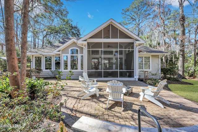 rear view of property featuring a patio, a sunroom, and an outdoor fire pit