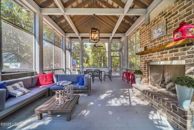 sunroom / solarium with an outdoor brick fireplace and vaulted ceiling with beams