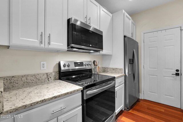 kitchen featuring white cabinetry, wood-type flooring, light stone countertops, and appliances with stainless steel finishes