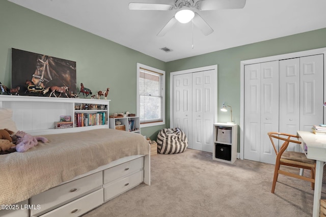 carpeted bedroom featuring ceiling fan and two closets