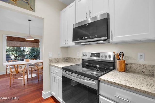 kitchen featuring white cabinetry, light stone counters, hanging light fixtures, hardwood / wood-style flooring, and stainless steel appliances