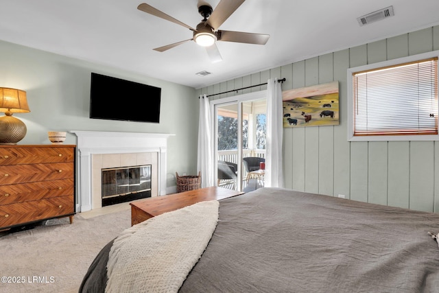 carpeted bedroom with ceiling fan, access to exterior, and a fireplace