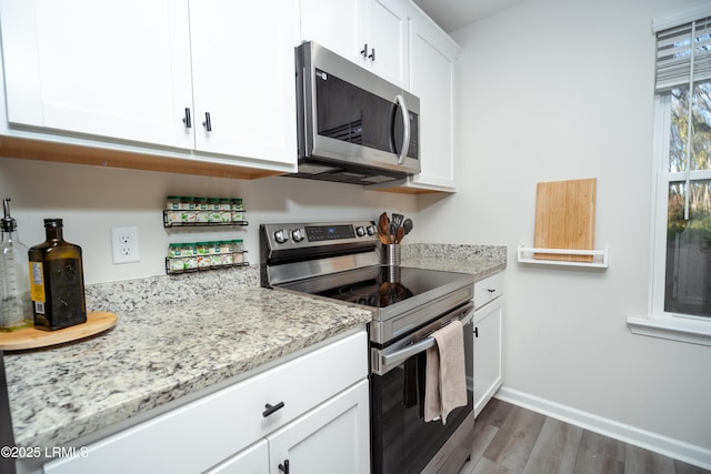 kitchen with white cabinetry, light stone counters, stainless steel appliances, and dark hardwood / wood-style floors